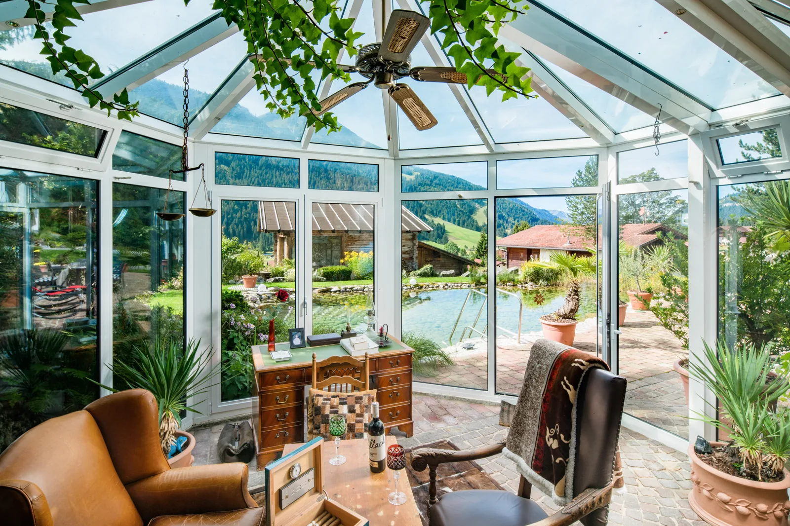 Das Fumoir im Wintergarten mit Ledersesseln und Blick in den Garten