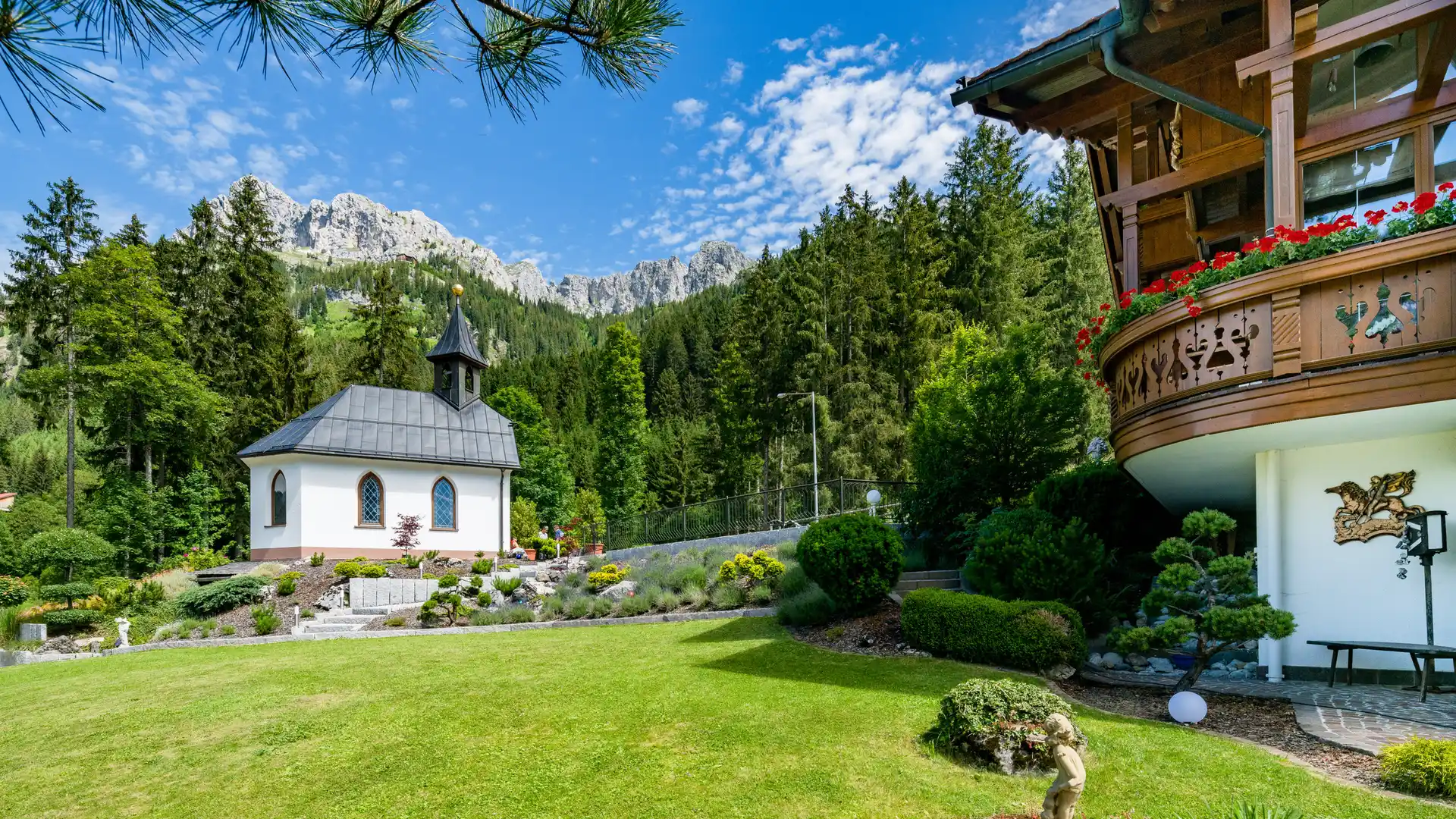 Kapelle und Garten des Sunneschlössli im Sonnenlicht, vor den Tannheimer Bergen