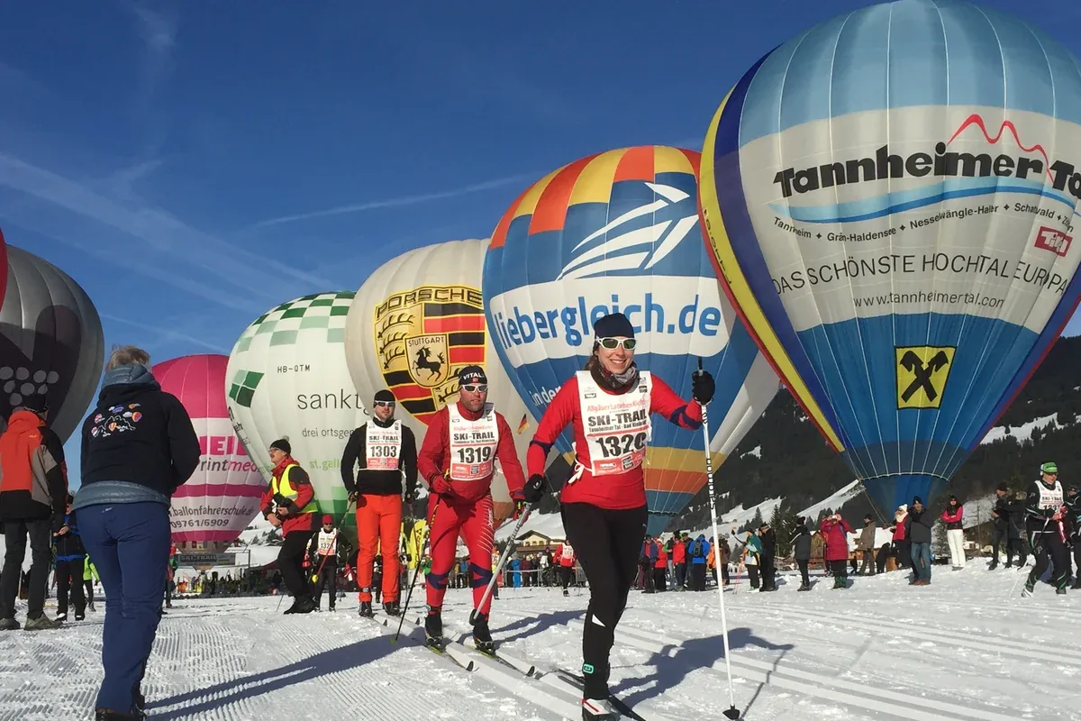 Cross-country skiers at the Ski-Trail in the Tannheimer Tal, hot-air balloons behind
