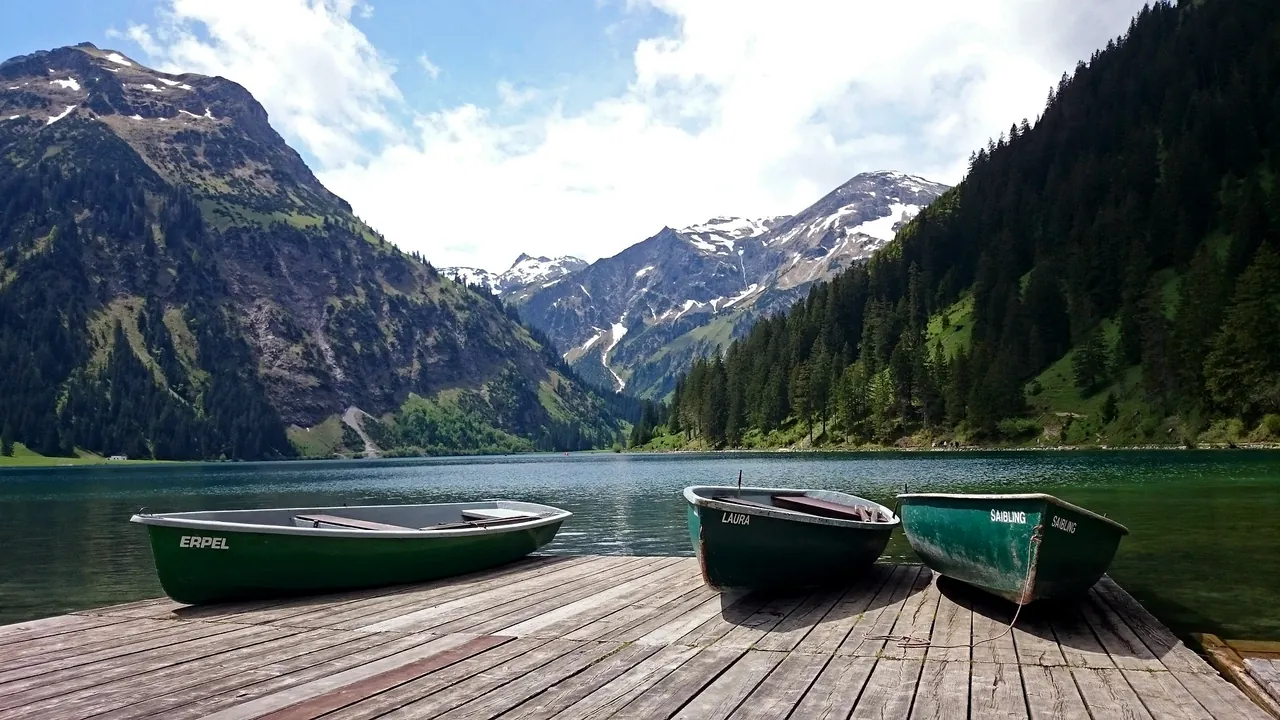 Der Vilsalpsee im Tannheimer Tal mit Ruderbooten am Steg und den Tannheimer Bergen dahinter